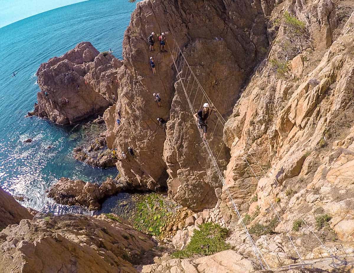 A person crossing a suspension bridge in the via ferrata Cala del Molí