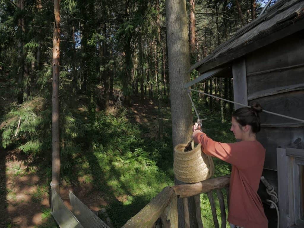 A person grabbing the basket that contains the breakfast in the Cabanes als Arbres