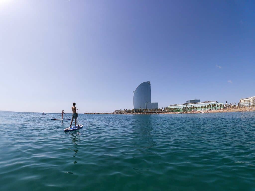 Two people doing stand up paddle in front of the Hotel W