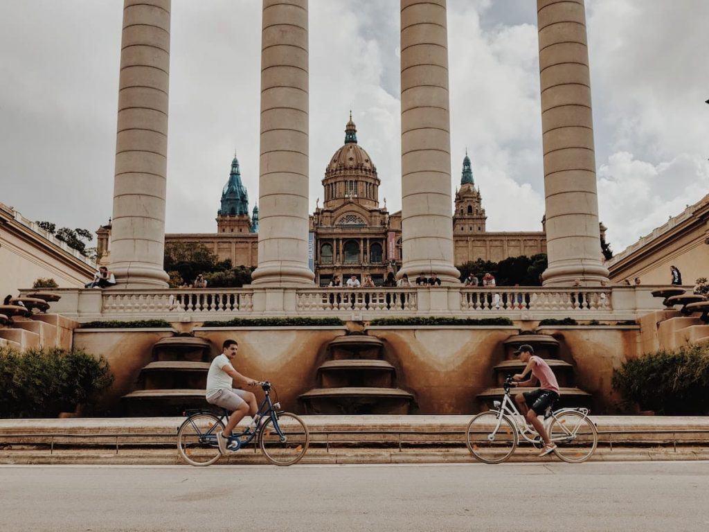 Two people cycling in front of the MNAC in Barcelona