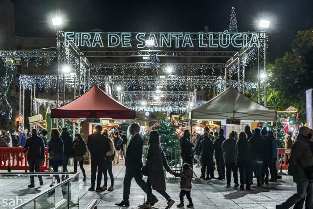 People walking in front of the entrance of the Christmas market Fira de Santa Llucia in Barcelona