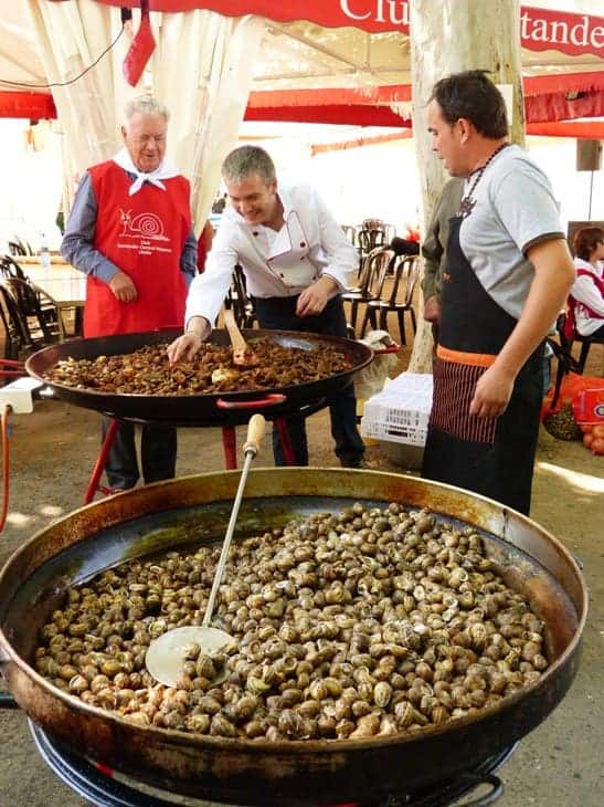 Three people cooking snails in the Aplec del Cargol festival in May in Lleida (Catalonia)