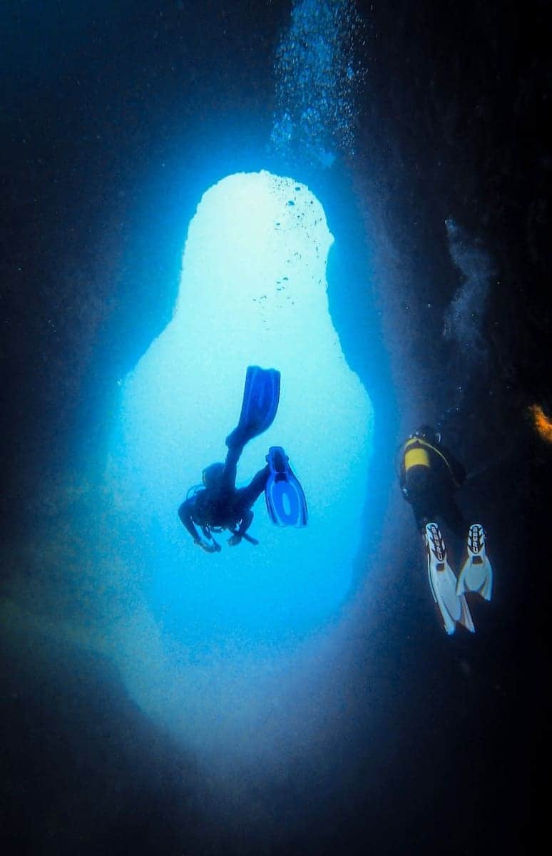Two divers crossing an underwater arch in the Costa de Montgrí (Estartit, Spain)