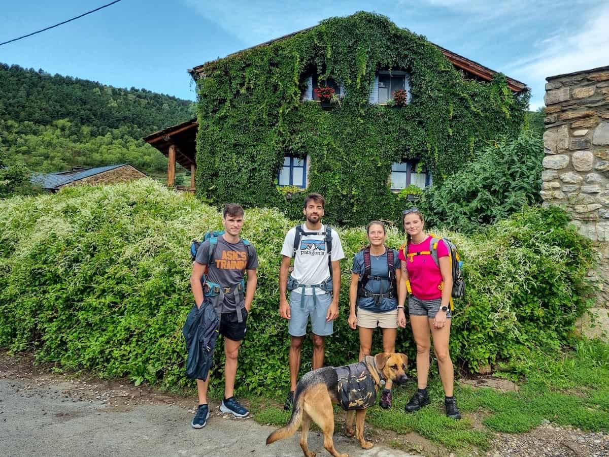 Four hikers in front of a house covered in plants in Eller (La Cerdanya)