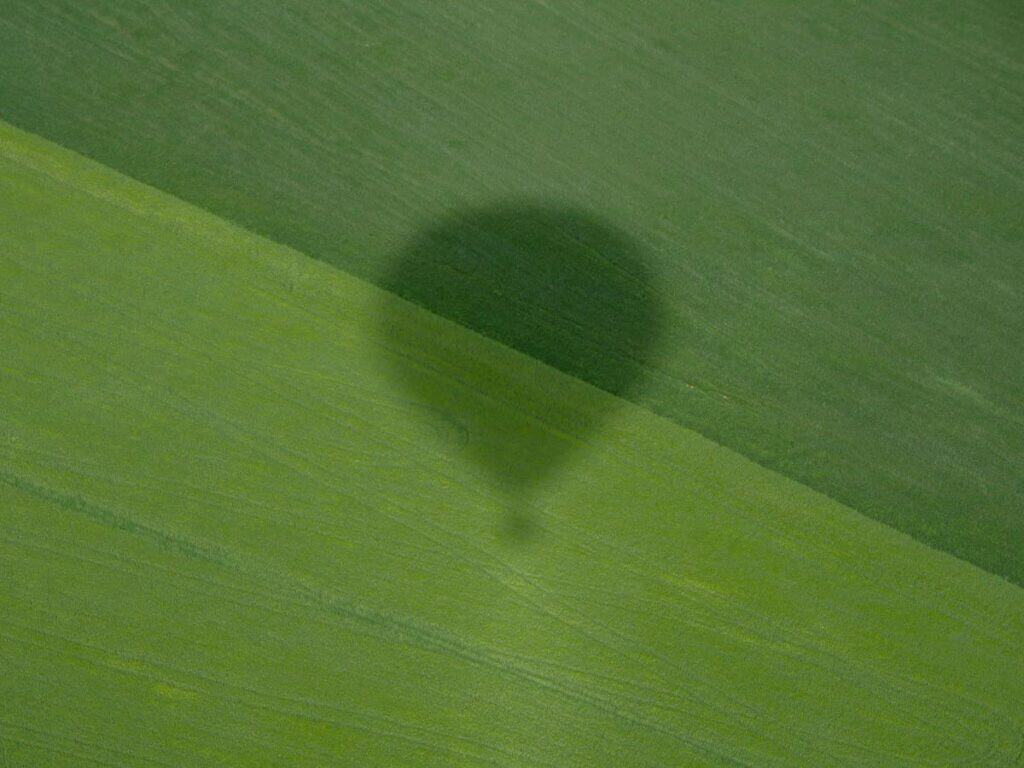 The shadow of the hot air balloon in a green field